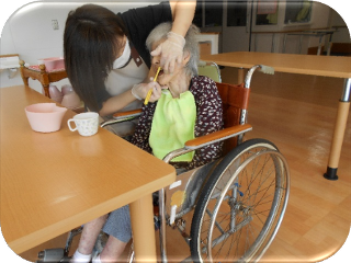 車椅子利用者が食卓で野菜を持ち、日常生活の場面